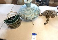 Overview of green porcelain half-circle lamp with brass frame and blue porcelain hanging lamp with chain on table