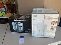 Boxed Calphalon 2-slot stainless steel toaster and Braun Deluxe Juice Extractor MP 80 boxes side by side.