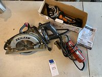 Wide view of the Skilsaw Model 77 worm drive circular saw and WORX Worxsaw in box with manual and accessories.