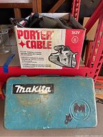Boxed Porter Cable 362V belt sander and closed Makita drill case showing Makita brand and wear on case