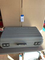 Closed gray hard plastic Skilsaw carrying case placed on flat surface, showing exterior with secure clasps and handle.