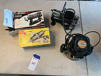 All four items in the lot displayed on a table: Sears Craftsman hobby tool kit box, Rotozip spiral saw box, Iwata air compressor, and Craftsman router with power cord.