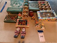 Full lot image showing boxes of Shiny Brite glass Christmas tree ornaments, loose ornaments, two See's candy Santas, and small holiday figurines.