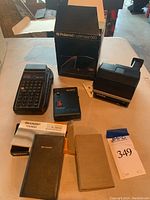 Overview of all items laid out on table including calculators, Walkman, and Polaroid accessory