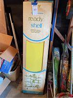 Boxes of Knape & Vogt Ready Shelf wall shelving boards, showing yellow shelf through packaging