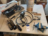 Full view of woodworking tools on a white table showing hand planers, cords, small clamps, Tuff Tool vise and vintage Dumore hand grinder.