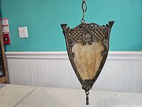 Front view of the slag stained glass lamp showing a trapezoidal amber glass panel within a decorative ornate metal frame.