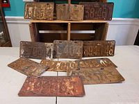 Overview photo of all 11 rusty, dented Ontario license plates from 1932 to 1964, showing various embossed plate numbers, rust and wear