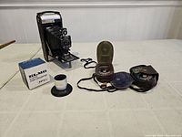 Full view of Kodak 1A Autographic camera, two light meters with leather cases, Elmo slide converter box, and film viewer on table.