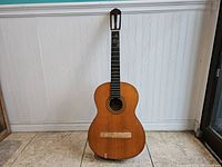 Front view of acoustic guitar shell standing upright with no strings or bridge attached