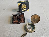 Photo showing compass inside its opened lid, leather case with flap open, and original box behind