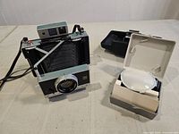 Camera open with bellows extended next to open portrait kit case