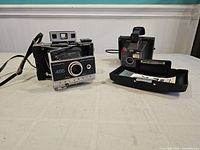 Front angle view of the Polaroid 455 camera with loose front panel and Polaroid Zip printer with accessories.