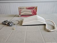 Side view of the white Contempra telephone with handset, cable, and original box in background.