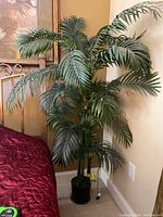 Artificial palm tree standing approximately 64 inches tall, showing realistic green plastic leaves and multiple stems in a black pot.