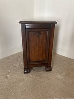 Front view of dark solid wood side table showing panel door and knob