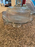 Side view of the glass cake serving plate with ribbed dome cover and knob handle showing the pedestal base.