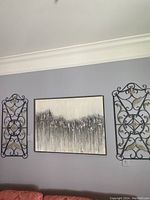 Full view of wall with framed abstract art centered between two metal wall panels with scrollwork and decorative accents.