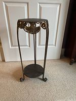 Full view of decorative metal plant stand against door background.