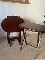 One TV tray set up and three folded and standing