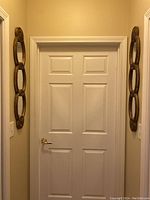 Two identical narrow mirrored wall hangings mounted on either side of a door, showing the overall look and size in context.