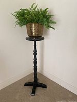 Wooden plant stand with green potted plant on top, showing overall style and use