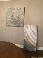 Two abstract canvas paintings displayed side by side; one square floral art, one rectangular abstract marble art.