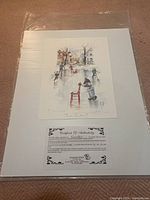 Photo showing the full print mounted on white mat board and sealed in plastic, featuring a winter scene with children playing on ice near a chair, signed by Julia Conlon.