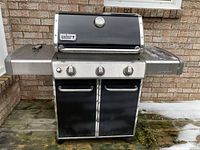 Front view of entire grill on deck showing hood, control panel, cabinet and wheels