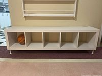 Front view of white laminated console cabinet with five open compartments and basketball in one compartment.