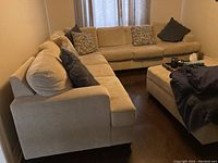 Full view of beige sectional couch arranged in L-shape with accent cushions