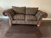 Front view of the ROWE upholstered couch showing the rolled arms, button tufting, and visible wood legs on dark flooring.