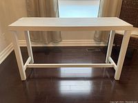 Full front view of the white wood desk showing its rectangular shape and crossbar stability supports.