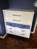 Painted wood dresser angled view showing white finish and wavy bottom drawers with black handles.