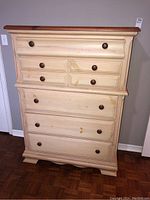 Front view of the wooden dresser showing seven drawers and a reddish-brown top.