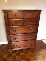 Front view showing six drawers with two smaller top drawers and four larger drawers below, featuring round and oval metal handles respectively.
