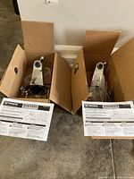 Two Moen faucets in opened boxes with instruction sheets visible for identification.