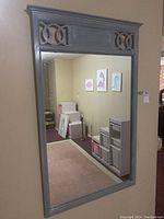 Front view of the large rectangular framed mirror showing the distressed gray wood frame and two decorative cutout panels at the top.