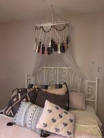 Full view of bed with decorative pillows and hanging canopy above the headboard