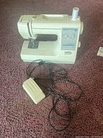 Front view of Kenmore 22 sewing machine including connected foot pedal and power cable on carpet.