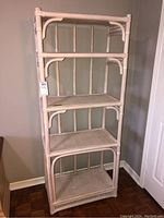 Front view of tall painted bamboo shelf with four shelves