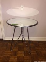 Full view of metal side table with mirror top showing circular mirrored surface and metal hairpin legs.