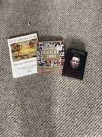 Three books laid on carpet: 'Fifty Golden Years', 'Canadian Gold 2002', and 'Playing with Fire' by Theo Fleury
