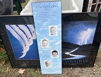 Three framed signs laid on the ground showing teamwork, innovation, and encouragement themes.