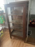 Front view of the wooden display cabinet with glass front door and shelves inside.