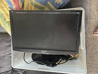 ViewSonic computer monitor placed inside a plastic bin, showing the front screen and part of the stand.