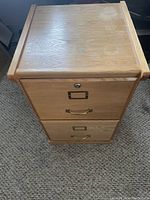 Front view of the two drawer wooden filing cabinet showing brass handles, metal label holders, and lock on top drawer.