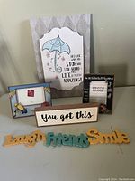 Photo of the lot showing various decorative signs and photo frames arranged on a surface.
