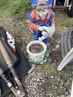 Decorative garden statue of boy watering ceramic pot filled with soil