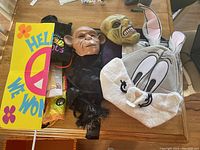 Overview of Halloween lot showing masks, costume pieces, and decoration sign on a table.